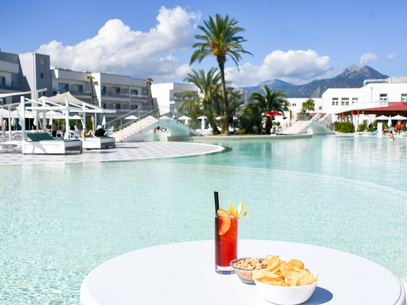 Snacks und ein Cocktail am Lagunenpool des Maritim Resort Calabria. Perfekte Auszeit mit Blick auf die Berge.
