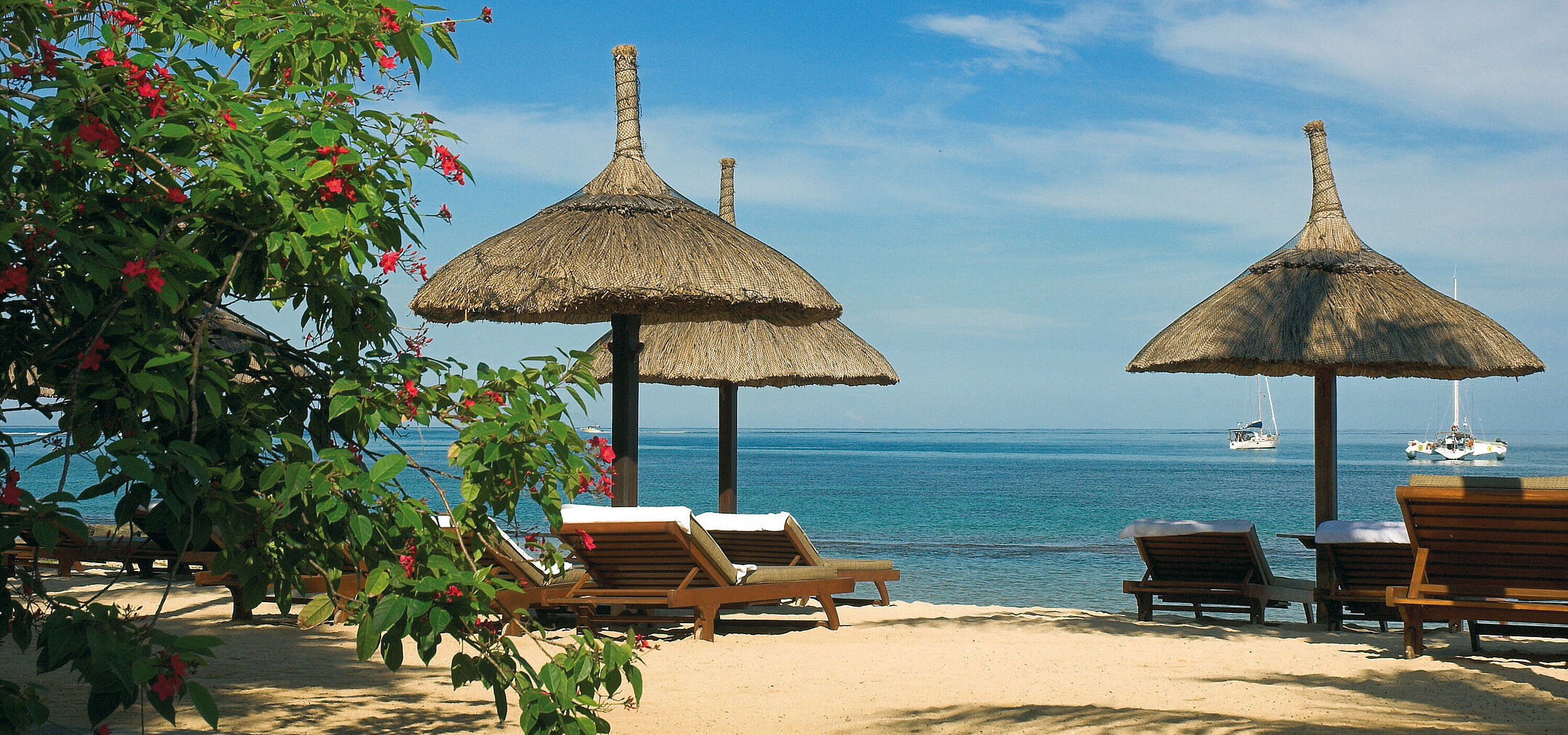 Strand mit Liegen Sonnenliegen unter Strohschirmen mit Meerblick im Maritim Hotel Mauritius