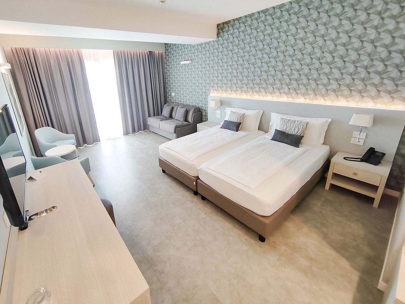Großzügiges Zimmer im Maritim Resort Calabria mit Twin-Bett, Sofa, Schreibtisch und hellen Farben