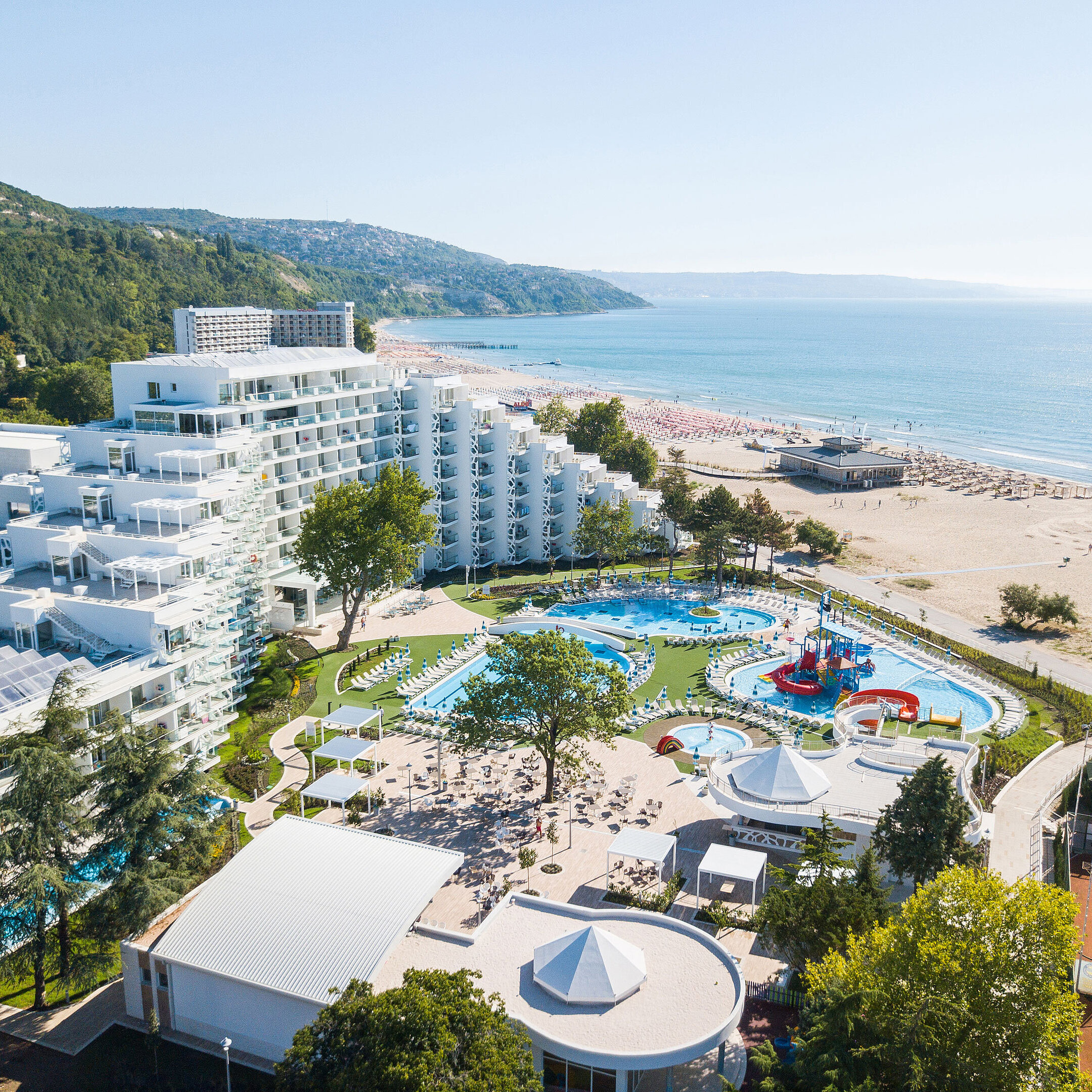 Luftaufnahme des Resorts mit Pools, Strand, modernem Hotelgebäude und Blick auf das Meer und die Küste