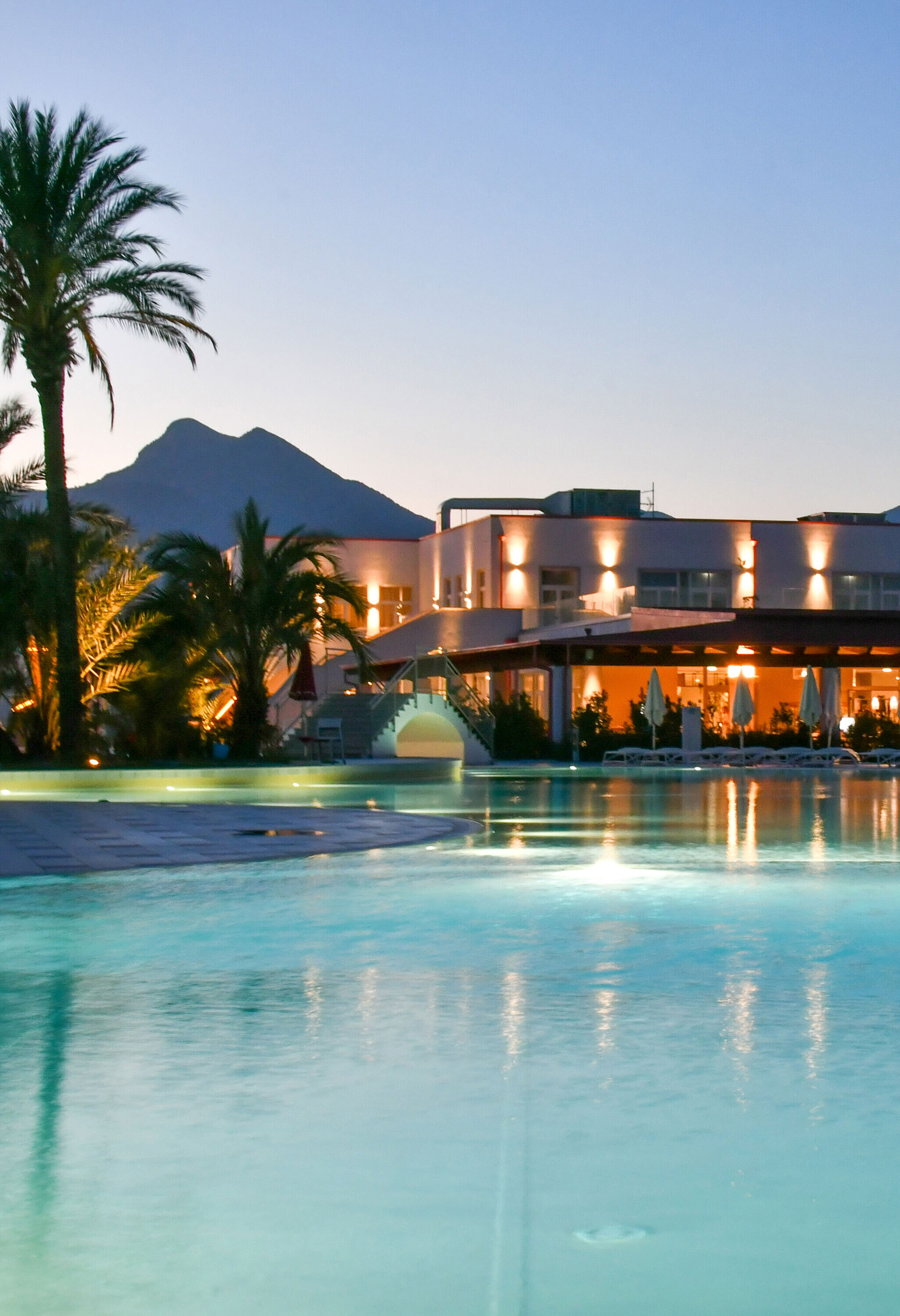 Poolbeleuchtung am Abend im Maritim Resort Calabria mit Palmen und Gebirgskulisse