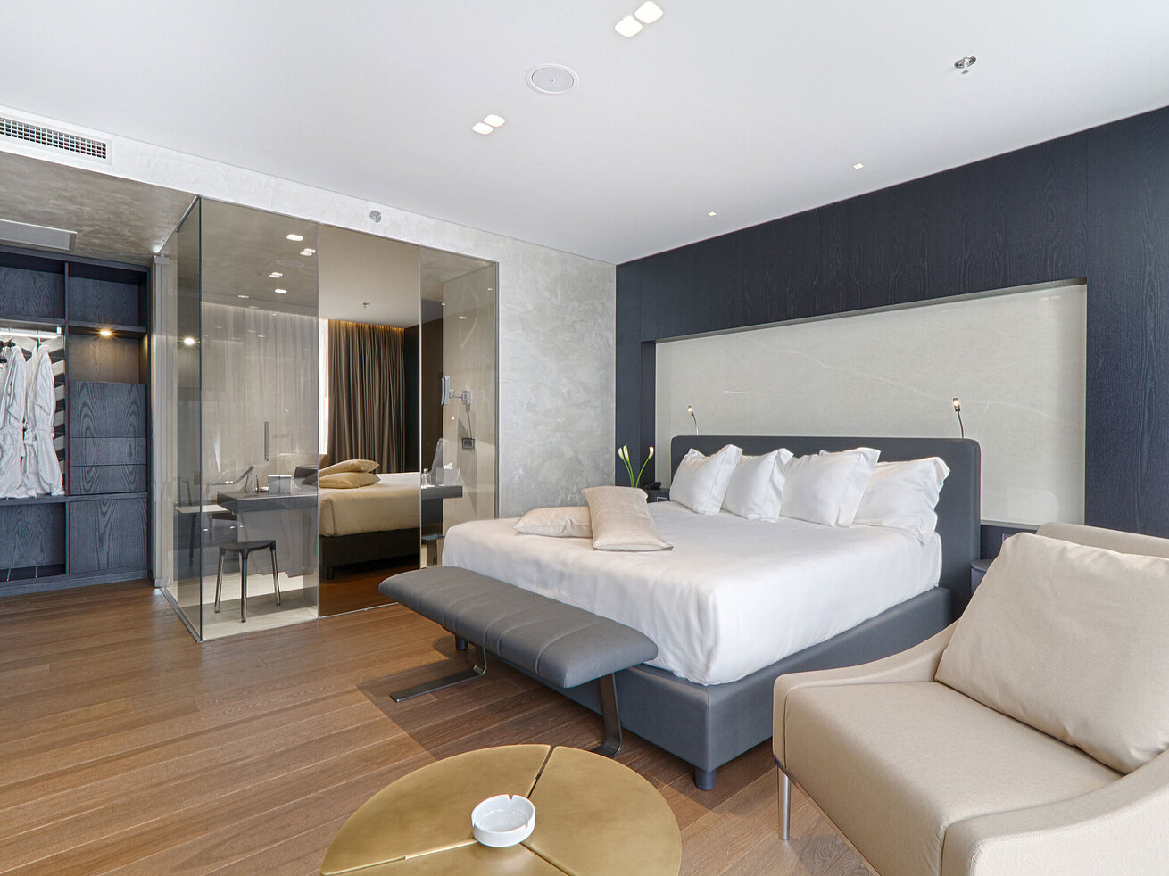 Großzügiges Doppelzimmer mit Sessel, Glastrennwand und modernem Design im Maritim Hotel Plaza Tirana