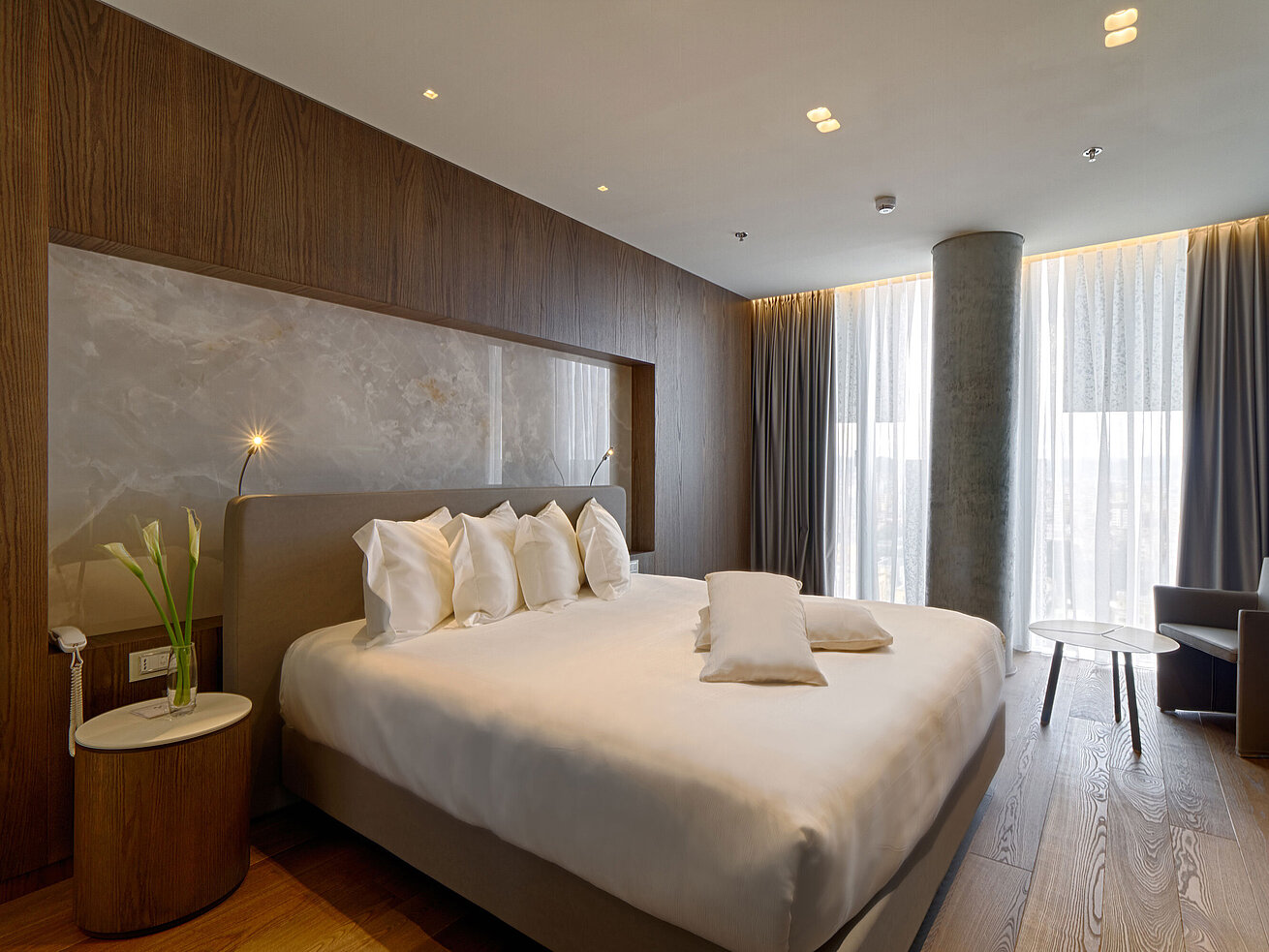 Suite Ruhiges Zimmer mit großem Bett, Natursteinwand und weichen Vorhängen im Maritim Hotel Plaza Tirana