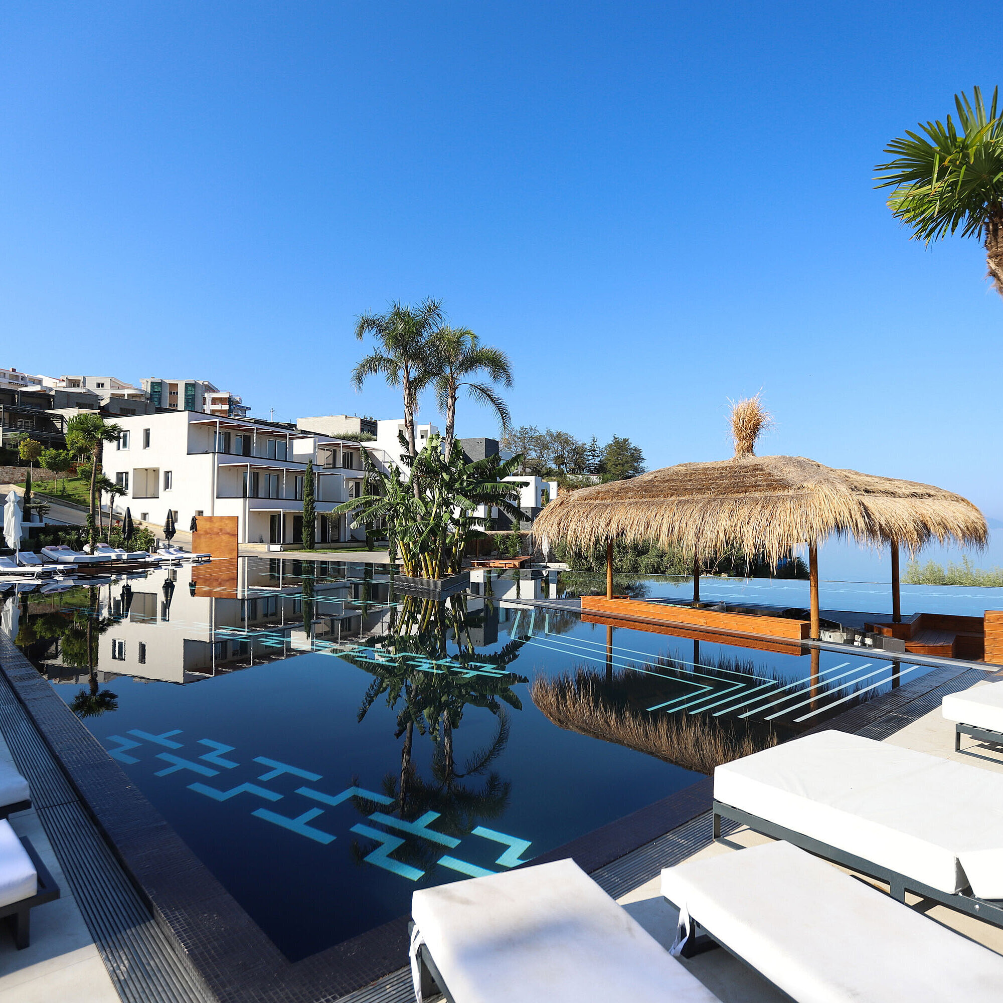 Exklusive Poollandschaft im Maritim Resort Marina Bay mit Palmen, Sonnenliegen und Meerblick